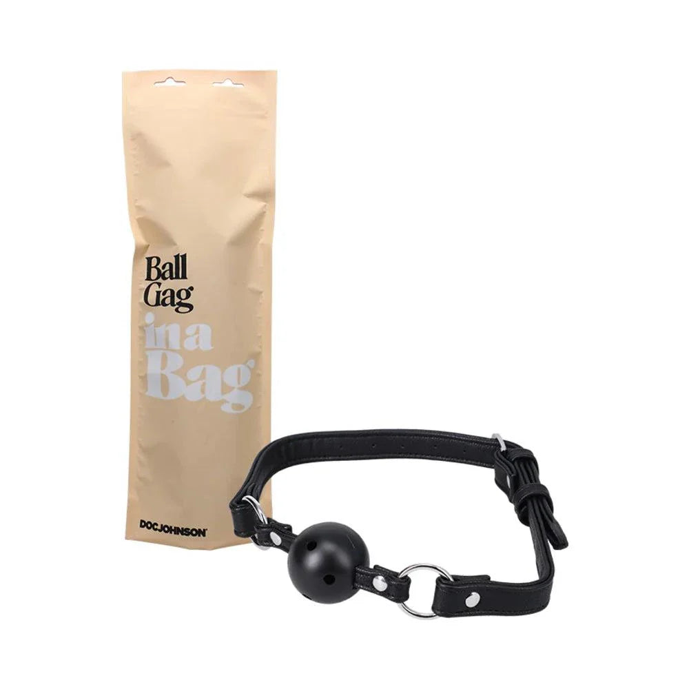 Doc Johnson Ball Gag in black breathable faux leather with oversized ventilated ball and adjustable strap next to beige storage bag