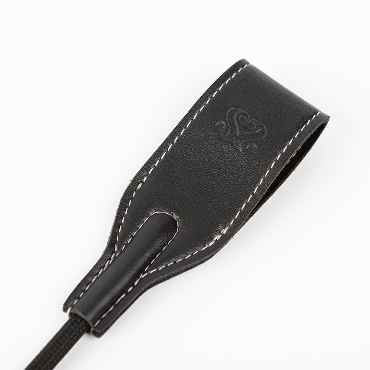 SEI MIO Rein In Desire Faux Leather Riding Crop tip with black stitched handle and embossed logo