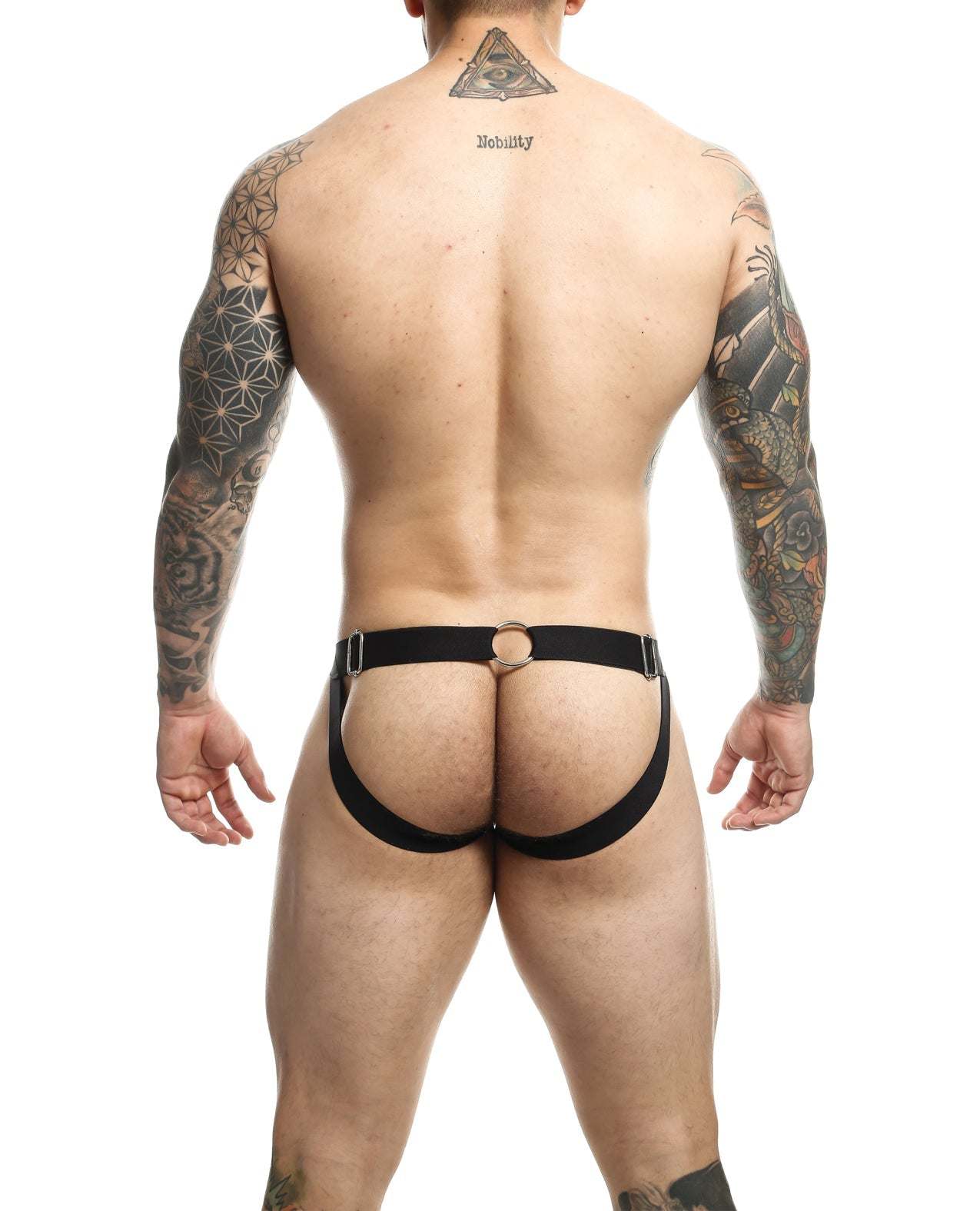 Rear view of a tattooed man wearing a black Dngeon Chain Jockstrap with metal ring detailing and wide straps.