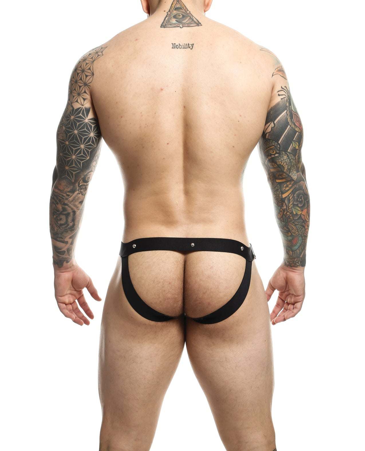 Rear view of a tattooed man wearing a black Dngeon Snap Jockstrap with metal rings and open back design.