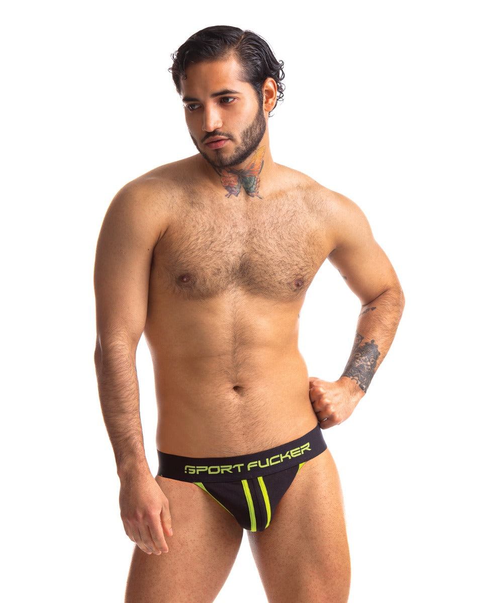 Man wearing Sport Fucker Jersey black athletic mesh jockstrap with neon green accents and branded waistband