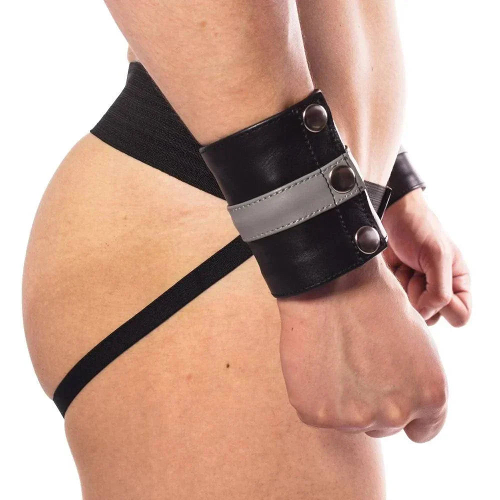 Black and gray leather wrist cuff with adjustable straps secured on a person's wrist and hip.