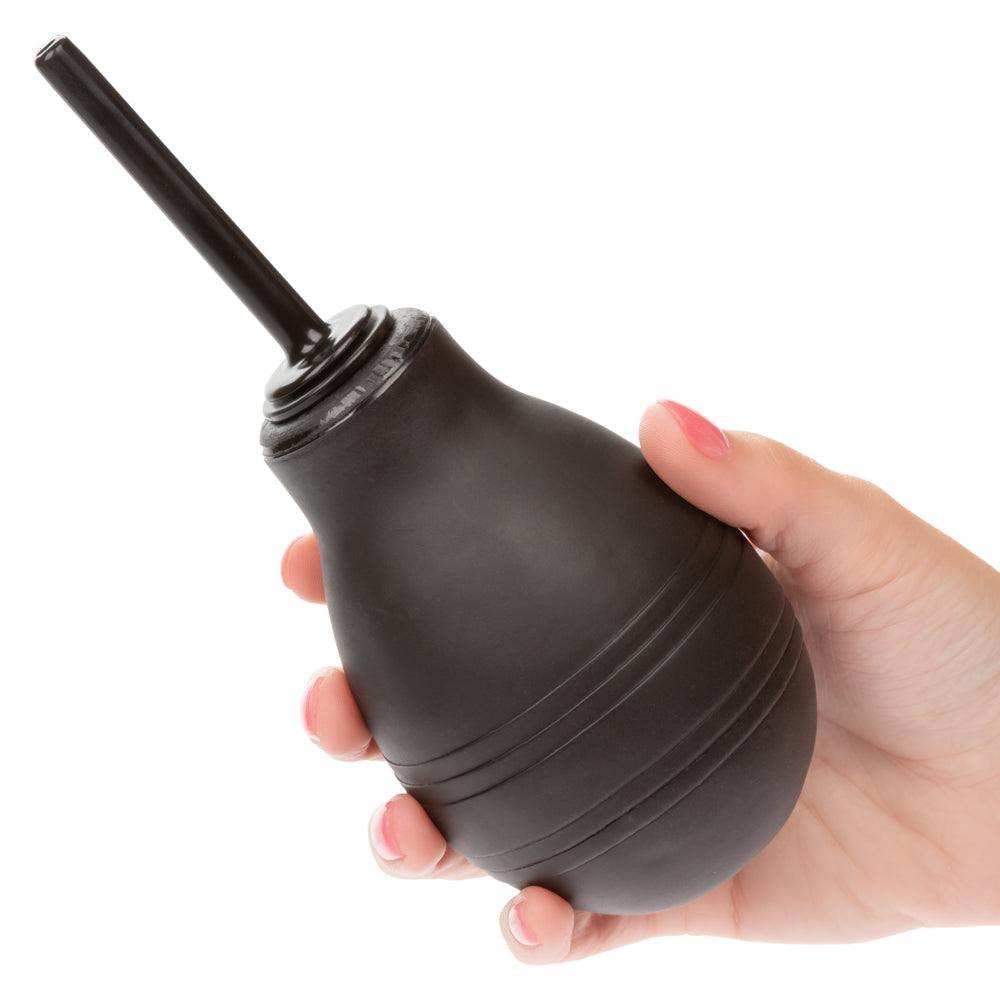 Hand holding a black One Way Anal Douche with slender nozzle and ergonomic squeeze bulb for personal hygiene and cleansing.