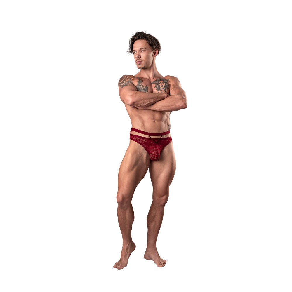 Male model wearing Male Power Lucifer burgundy cutout strappy thong with vintage floral lace and secure elastic straps S/M size