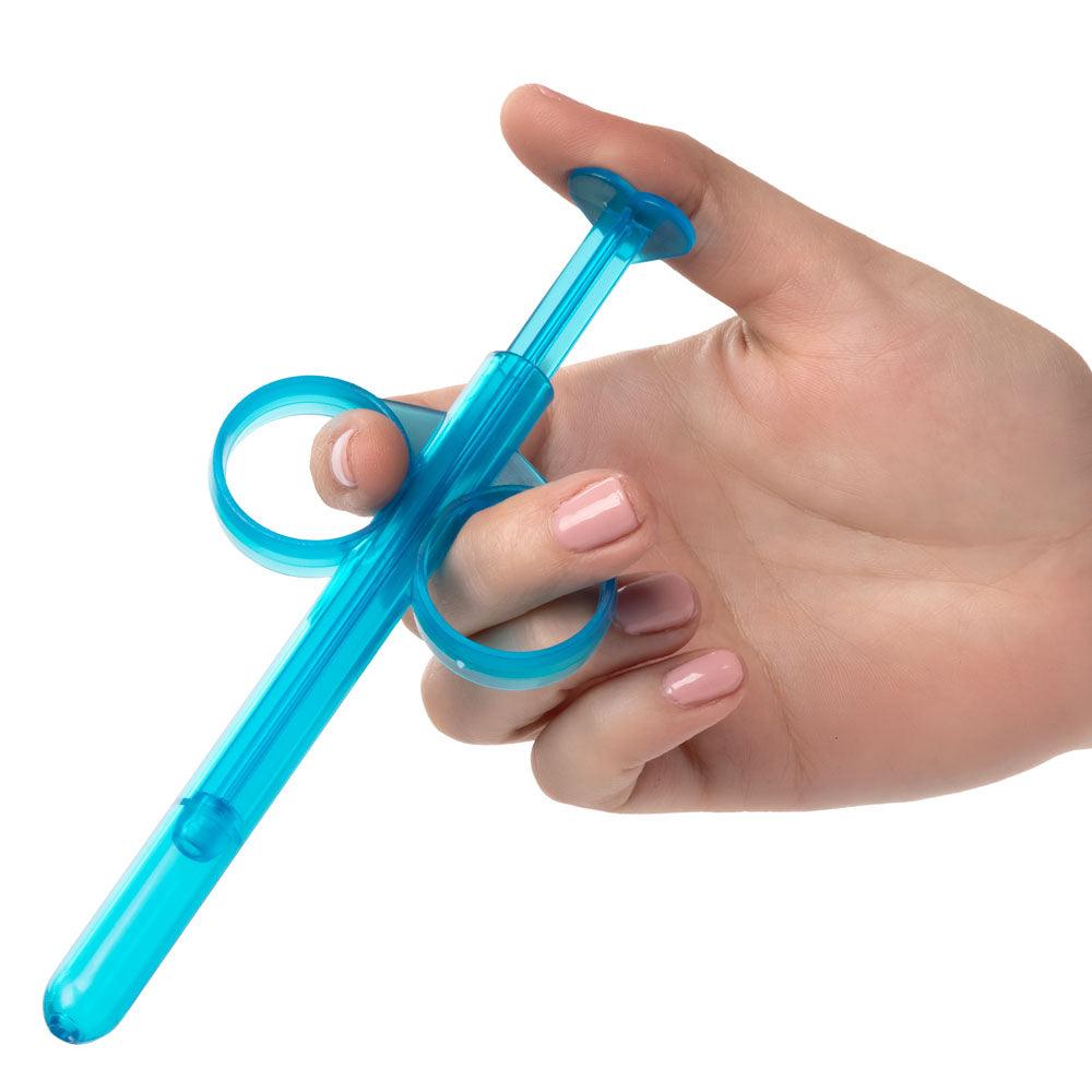 Hand holding the reusable and refillable Lube Tube - Blue with finger loops and plunger for precise lubrication control