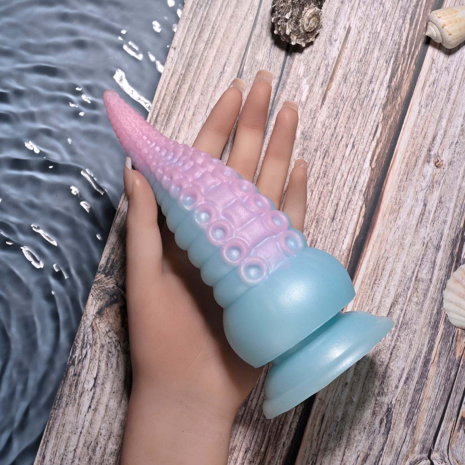 Stuck on You Multicolor flexible silicone tentacle toy with suction base in pastel pink and blue colors held in hand on wooden surface near water