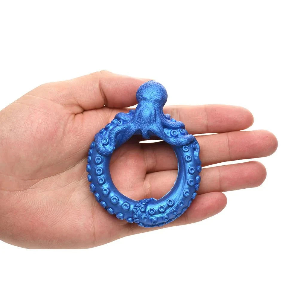 Blue silicone cock ring shaped like an octopus, held in a hand.