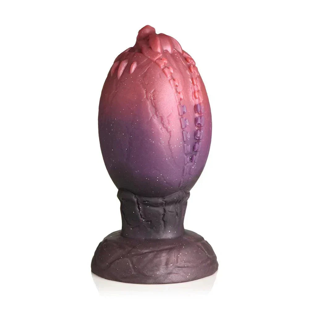XL Creature Cocks Dragon Hatch silicone egg with glittery dark red and brown finish, textured ridges, and dragon-head tip for fantasy play.