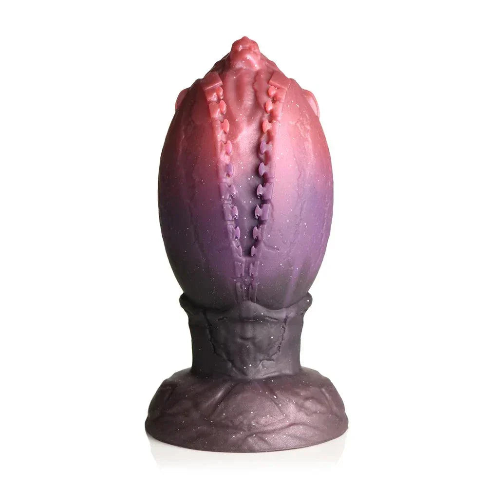 Creature Cocks Dragon Hatch Silicone Egg XL with glittery finish in dark red and brown hues, featuring zipper-like ridges and tapered dragon-head tip for fantasy play.