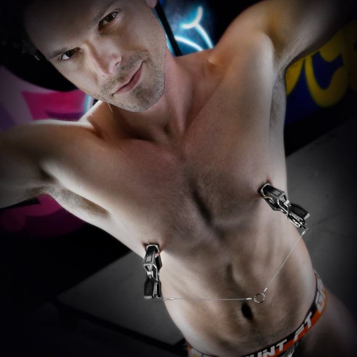 shirtless man using Fort Troff Hardwire Hangers nipple clamps with metal chain and aluminum O-ring attachment