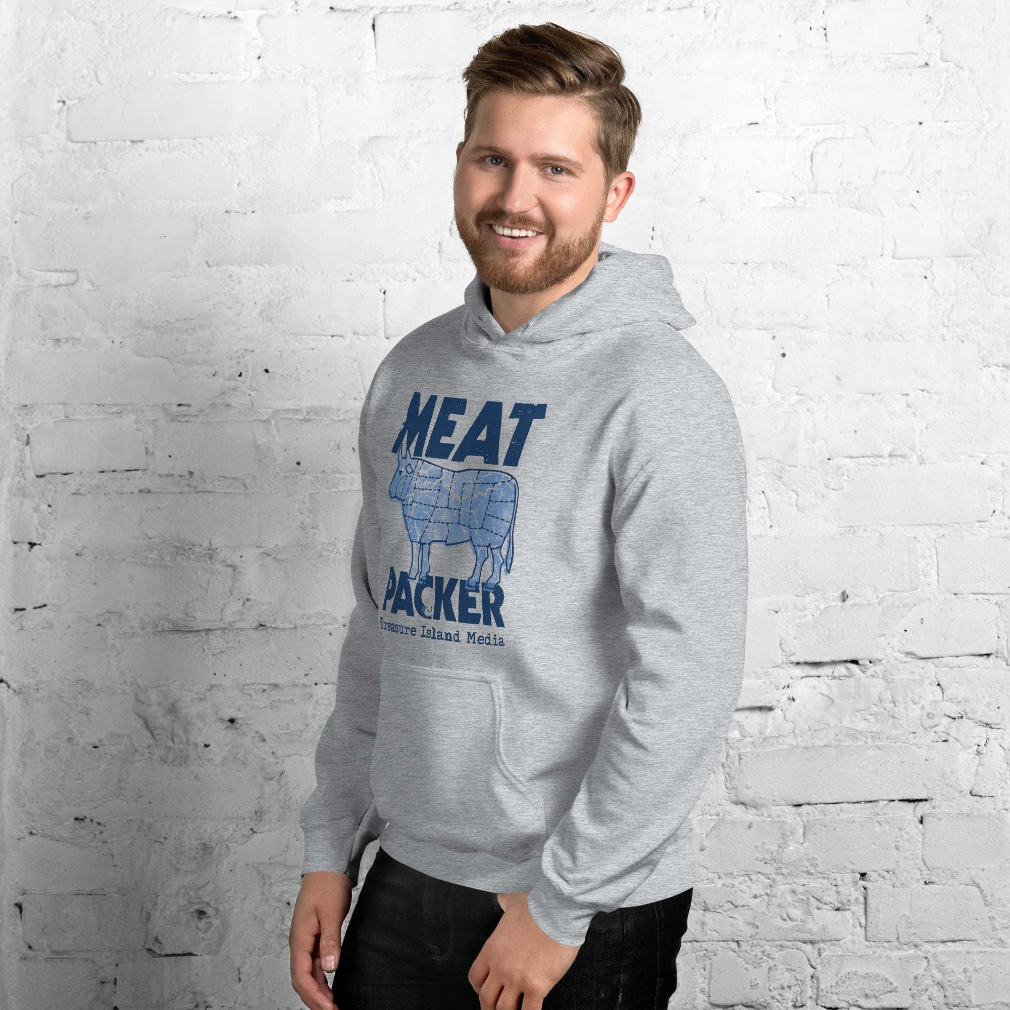 Meat Packer Hoodie in light gray with blue graphic design, worn by a person against a white brick wall.