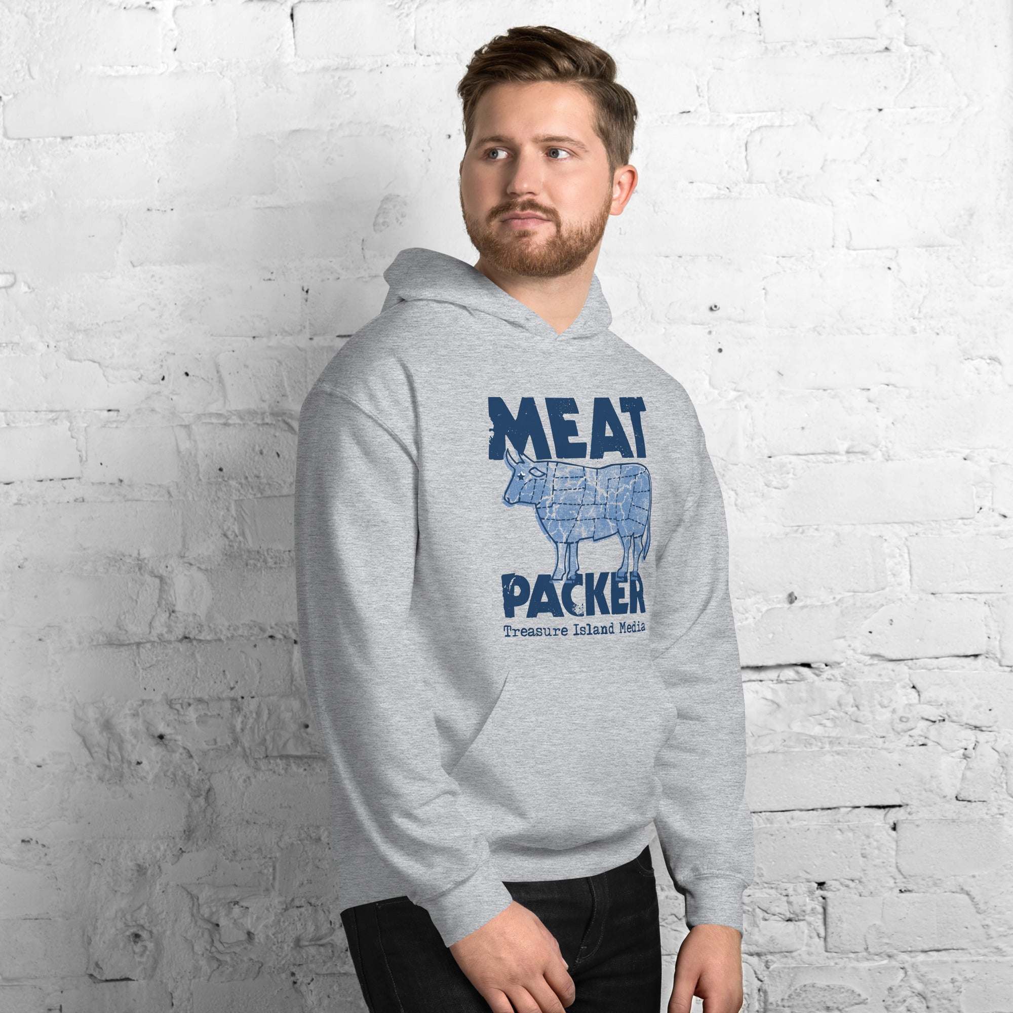Man wearing Meat Packer Hoodie in gray against brick wall backdrop.
