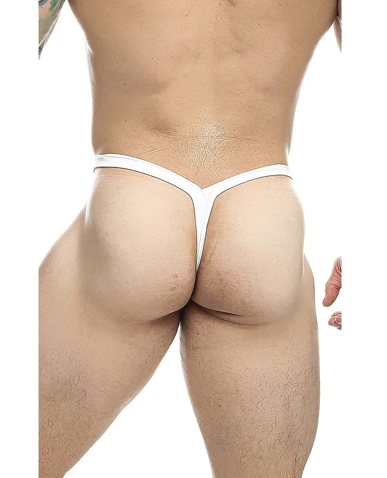 Male model wearing white Male Basics Y Buns Thong showcasing slim V-strap design and minimal rear coverage.
