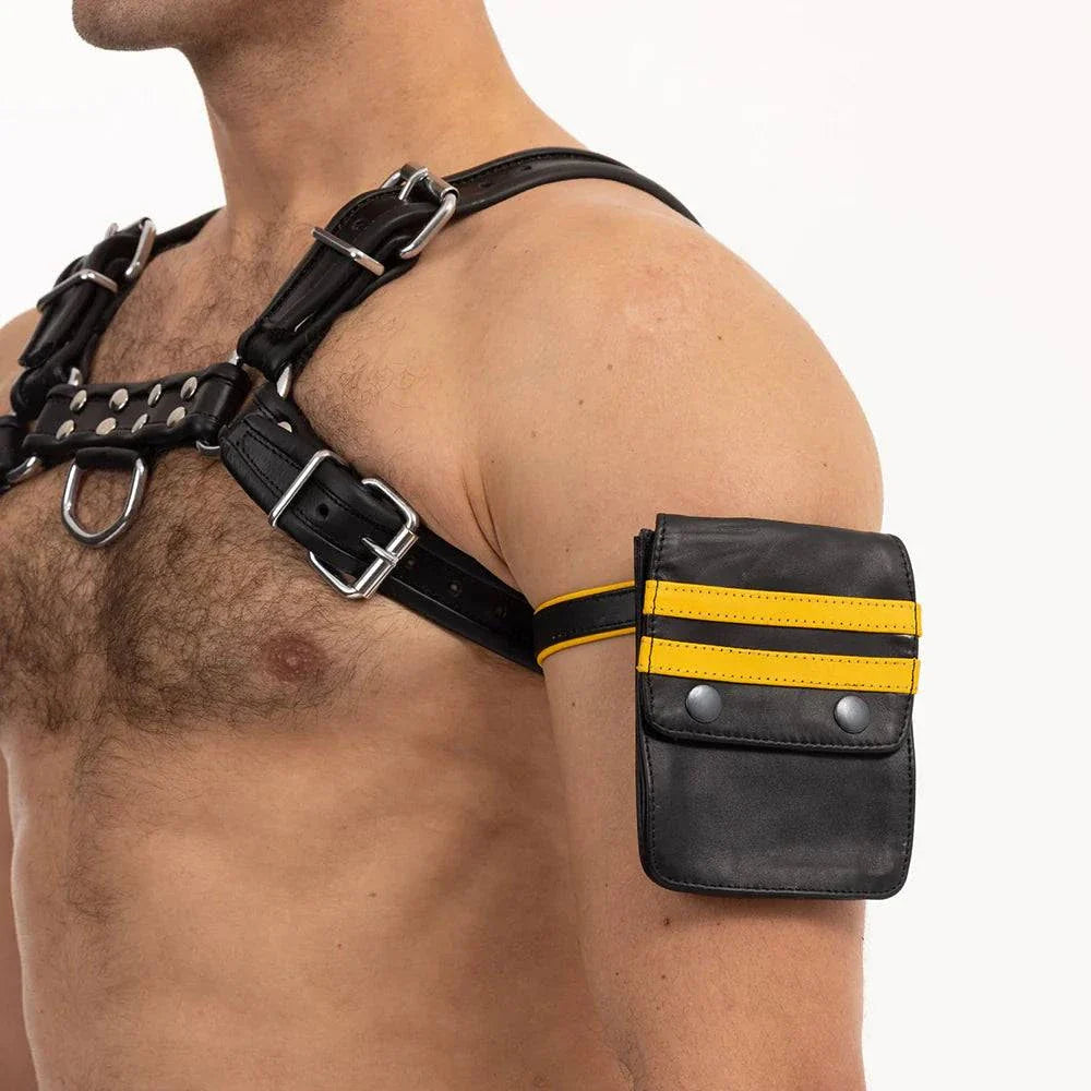 black leather Prowler RED Pouch with yellow stripes worn as an armband pouch on a man's upper arm with black leather harness straps