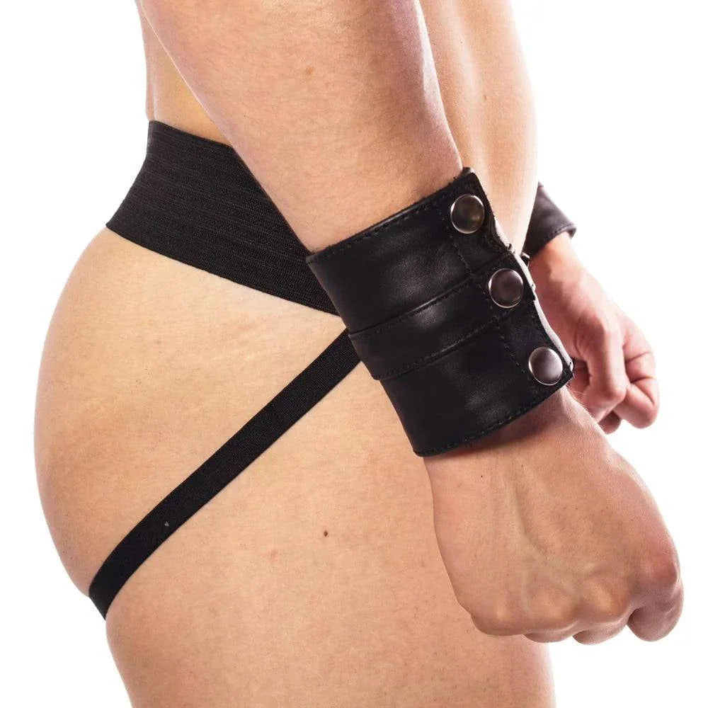 Black leather wrist cuff with adjustable strap and snap closures on a person's wrist
