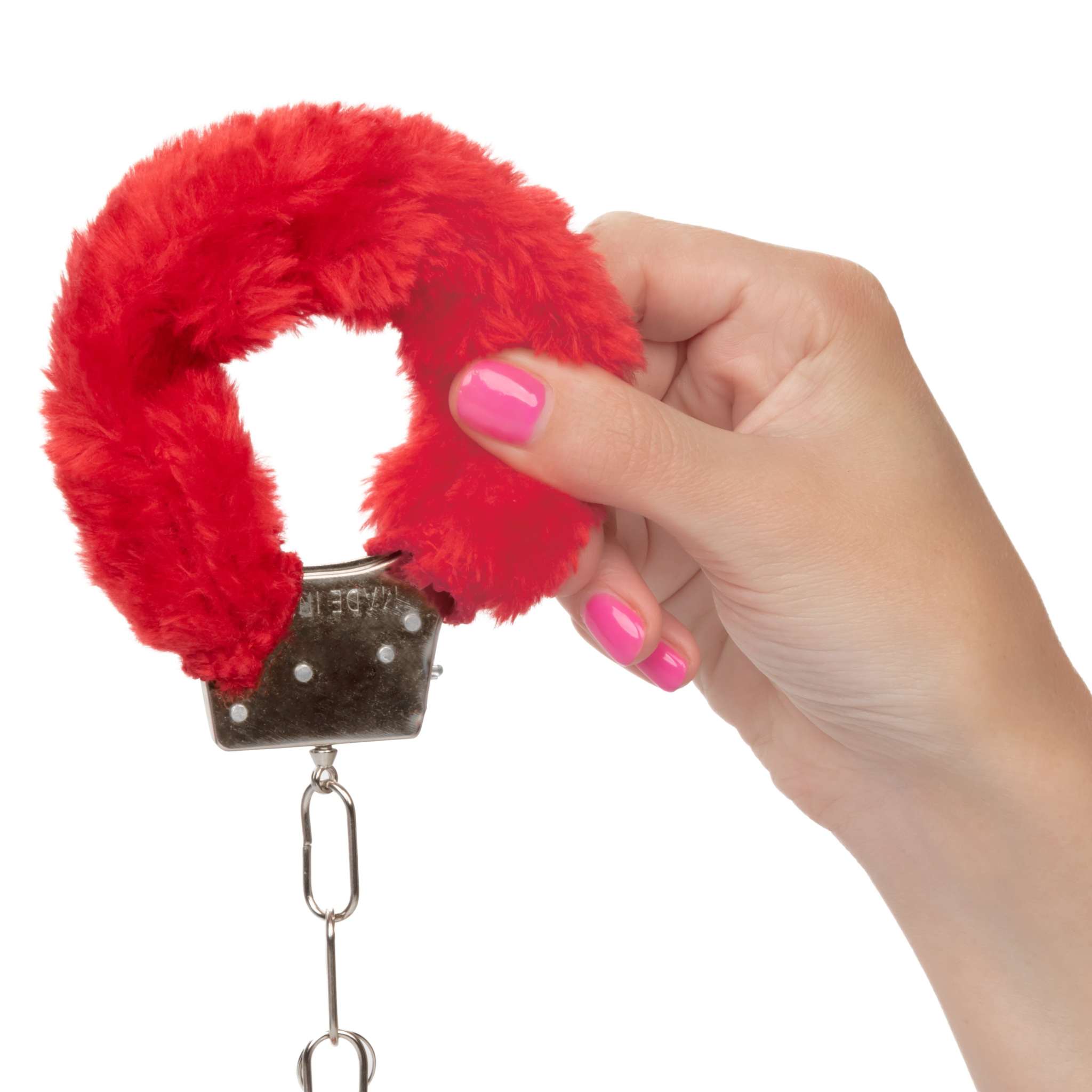 Hand holding red playful furry cuffs with soft faux fur and metal handcuff design