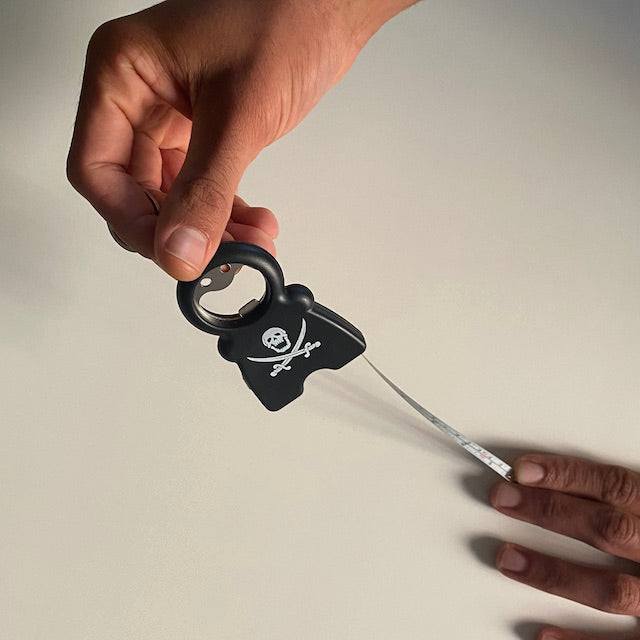 TIM 4-in-1 Keychain with bottle opener, flashlight, and retractable measuring tape held in hand against neutral background